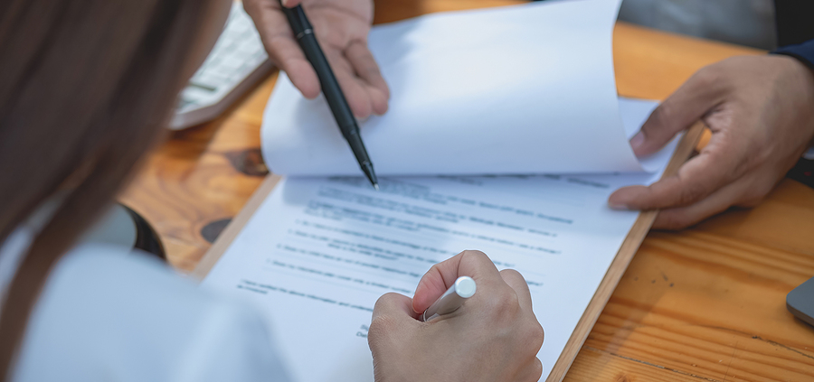 A person writing on paper with a pen.