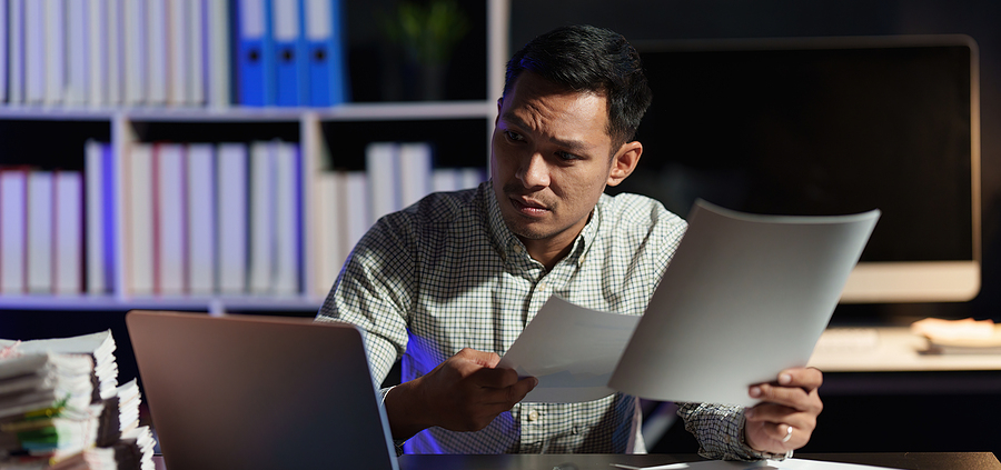 A man sitting at his desk looking at papers.