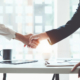 Two people shaking hands over a table.