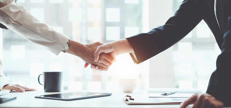 Two people shaking hands over a table.