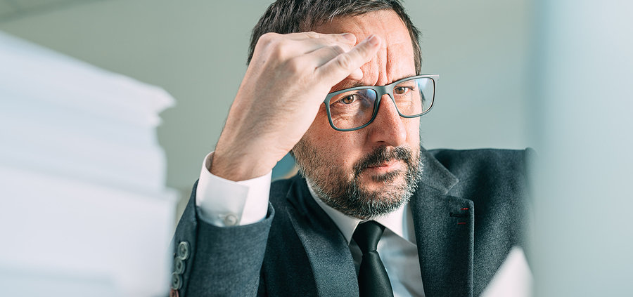 A man in suit and tie holding his head.