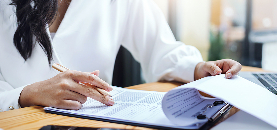 A woman is writing on paper while sitting at her desk.