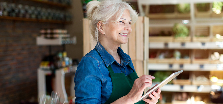 A woman in an apron holding a tablet.