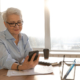 A woman sitting at a table with papers and a cell phone.