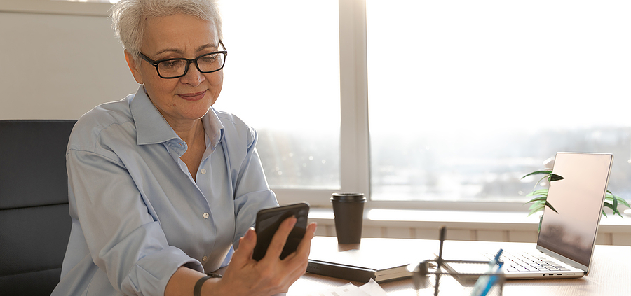 A woman sitting at a table with papers and a cell phone.