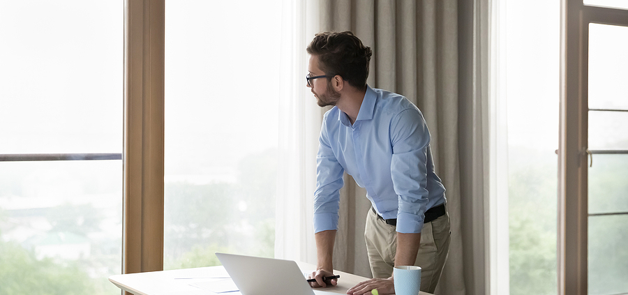 A man standing at the table looking at his laptop.