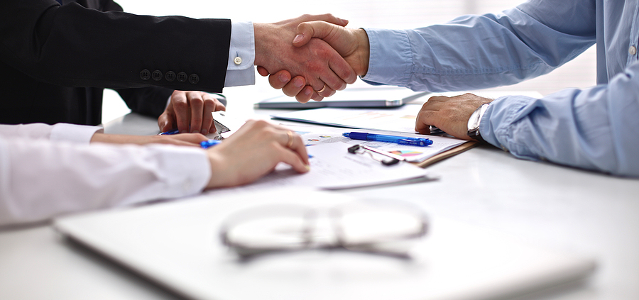 A group of people sitting at a table shaking hands.