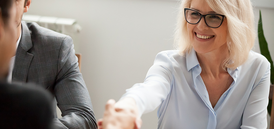 A woman shaking hands with another person at a table.